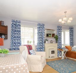 A living room with blue patterned curtains a polka dot tablecloth and a white armchair at No 1 The Heathers Rosecraddoc Lodge near Liskeard