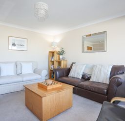 A living room with two sofas a wooden coffee table a bookshelf and a wall mirror at Tegfan in Trearddur Bay