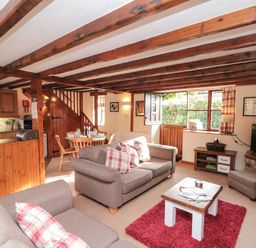 A living room with sofas cushions coffee table dining table and kitchen area at Goathland Cottage in Ruswarp near Whitby