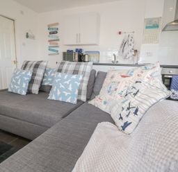A grey sofa with patterned cushions in a kitchen living area at Bracken Barn Cottage in Widdrington near Amble