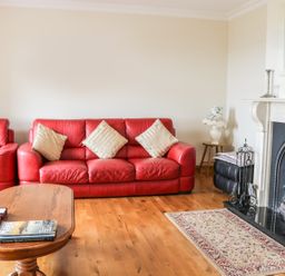 A living room with red sofas a wooden coffee table a fireplace and a small rug at McGuire's Cottage in Barnatra County Mayo