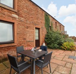 An outdoor area with a table and chairs at Hayloft Cottage in Bolton Low Houses