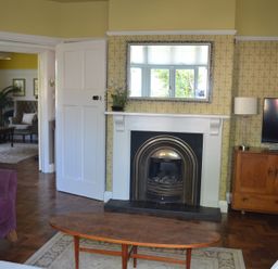 A living room with a fireplace mirror television wooden cabinet and coffee table at Lily House in Minehead