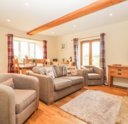A living room with grey sofas and a wooden dining table near windows with checkered curtains at Higher Whiddon Farm Whiddon Well Ashburton near Newton Abbot
