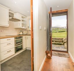 A kitchen with white cabinets and wooden countertops next to an open wooden door leading outside at Higher Whiddon Farm Whiddon Well Ashburton near Newton Abbot