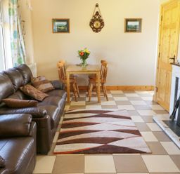 A living room with brown leather sofas a small wooden dining table with chairs and a fireplace at Clash-Brack in Dungarvan County Waterford