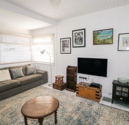 A living room with a sofa table lamp wooden coffee table television and wall art at Driftwood Polzeath near Wadebridge