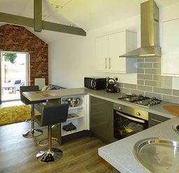 A kitchen and dining area with bar stools and cooking appliances at White Cottage Annexe in Tenby