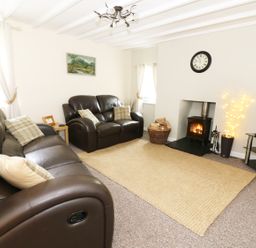 A living room with brown leather sofas a wall clock a fireplace and a television at Penglanowen Fawr in Llangwyryfon near Aberystwyth