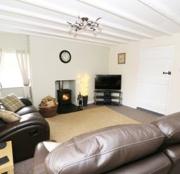 A living room with leather sofas a wood burner TV and a carpet at Penglanowen Fawr in Llangwyryfon near Aberystwyth