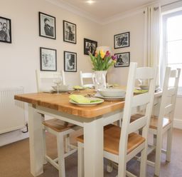 A dining room with a wooden table set with plates glasses and a vase of flowers at Tremanners in St  Agnes