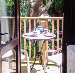 A small outdoor table set with teapot and cups on a wooden deck with two white chairs at Groom Cottage Poughill near Bude