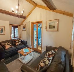A living room with two leather sofas a wooden coffee table and framed pictures on the walls at Groom Cottage in Poughill near Bude