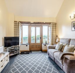 A living room with a sofa television and a patterned rug at The Granary in Llanfair Caereinion near Welshpool