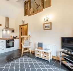A kitchen and living area with a wooden chair and a television on a stand at The Granary Llanfair Caereinion near Welshpool