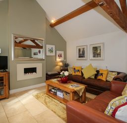 A living room with brown leather sofas wooden coffee table and wall mirror at The Milking Parlour in Yarpole near Leominster