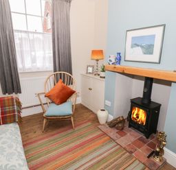 A small sitting room with a wood-burning stove chair and cabinet at 24 College Lane in Stratford-Upon-Avon