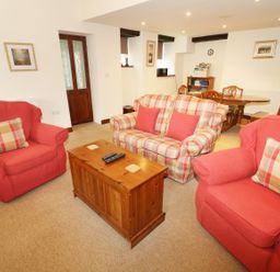 A living room with red armchairs a plaid sofa and a wooden coffee table at Kingfisher Barn in Staveley near Windermere