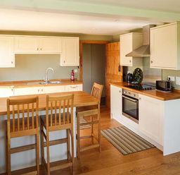 A kitchen with wooden countertops and chairs and a stove at Glebe Farm Cottage in Llandegveth near Cwmbran