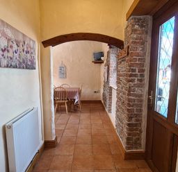 A hallway with tiled floor a wooden arch and a dining area with table and chairs at Swallow Cottage in Llanboidy