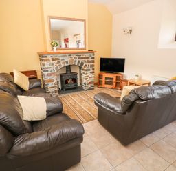A living room with leather sofas a stone fireplace and a television at Hill Top Farm Cottage in Martletwy near Narbeth