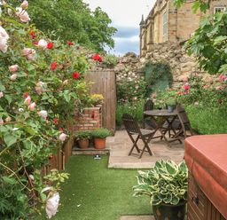 A garden with wooden chairs and table surrounded by flowers and plants at Beech View in Malton