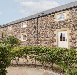 An exterior view of a stone building with windows and a door at Granary Stone House in Embleton