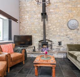 A living room with a wood stove and furniture at Pear Tree Cottage Mark near Burnham-on-Sea