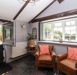 A room with two armchairs and a table at Pear Tree Cottage Mark near Burnham-on-Sea
