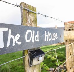 A fence with a sign that reads The Old House and a small light attached at The Old House in Llanidloes