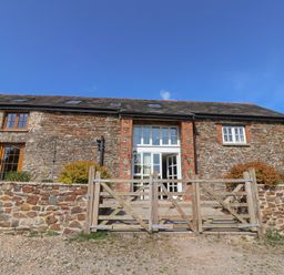 A stone building with a wooden gate at West Bowden Farm in Knowstone near South Molton