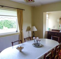 A dining room with a table set with candles chairs a lamp a sideboard and a window at Eileen's in Aughavas near Mohill County Leitrim