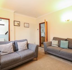 A living room with two grey sofas and cushions and doors leading to other rooms at 5 Melinda Cottages in East Runton near Cromer