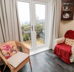 A room with two chairs and a glass door leading to an outdoor patio at Bunty's Place in Chatton near Wooler