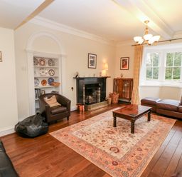 A living room with leather sofas a wooden coffee table a fireplace and a bay window at Eden House in Edenhall near Penrith