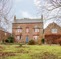 A front view of a brick house with a blue door and bay windows at Eden House Edenhall near Penrith