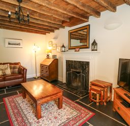 A living room with a leather sofa wooden coffee table fireplace and television at Penuwch Fach in Aberystwyth