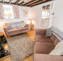 A sitting room with two sofas a rug wooden floor and a fireplace at Bron Heulog Cottage in Llangoed near Beaumaris