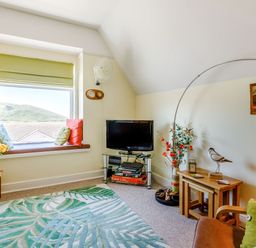A living room with a window seat with cushions and a mountain view at Glenwood in Woolacombe