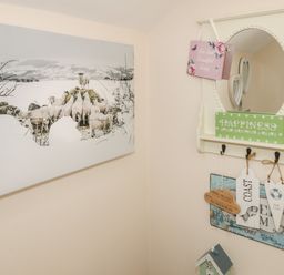 A corner with a wall mirror, decorative signs, and a large canvas print of sheep at The Store Rooms in Whitby