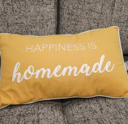 A yellow cushion with the words happiness is homemade on a gray sofa at The Store Rooms in Whitby