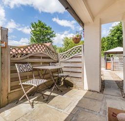 A small outdoor patio with a table and two chairs next to a wooden fence at Willow Cottage in Ulrome near Skipsea