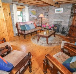 A living room with wooden furniture stone walls and a fireplace at An Nead in Ballinknockane near Dingle County Kerry