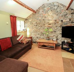 A living room with a sofa and television at Sonya's Cottage in Anthorn, Solway Firth