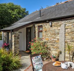 A cottage exterior with a table and chairs in East Taphouse