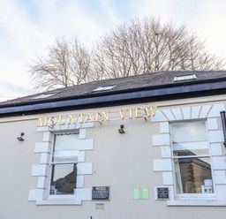 Exterior of a building with two windows and gold letters spelling mountain view at Mountain View in Penmaenmawr