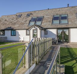 The exterior of a house with a ramp and lawn at Primrose Cottage in Aldingham