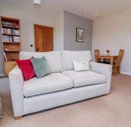 A living room with a sofa and dining table at Pound Cottage in Huntshaw near Great Torrington