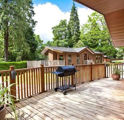 An outdoor deck area with a barbecue grill and a planter at Beech Hill Lodge (Beech Hill 9) at Fallbarrow Park, Bowness-on-Windermere