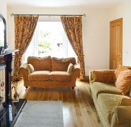 A living room with two sofas a fireplace and patterned curtains at Lovers Lodge in Kilkenny County Kilkenny